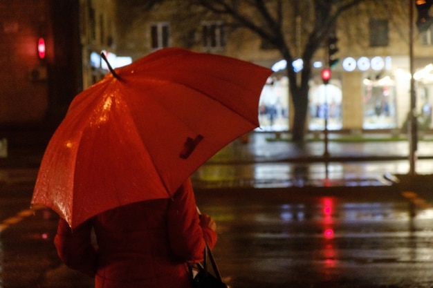 Foto serata piovosa una silhouette di donna con ombrello e traffico in esecuzione con gocce di pioggia autunnale