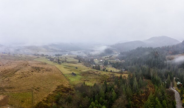 Rainy foggy and gray weather in the mountain valley of the Carpathians in Ukraine in small village Aerial panoramic drone shot