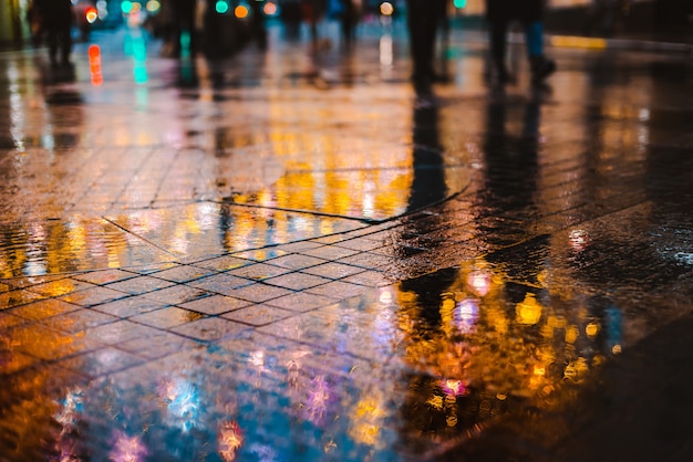 大都市の雨の夜、濡れた路面の光の反射。