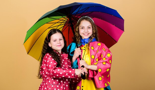 Rainy weather with proper garments bright umbrella it is easier to be happy together be rainbow in someones cloud rainy day fun happy walk under umbrella kids girls happy friends under umbrella