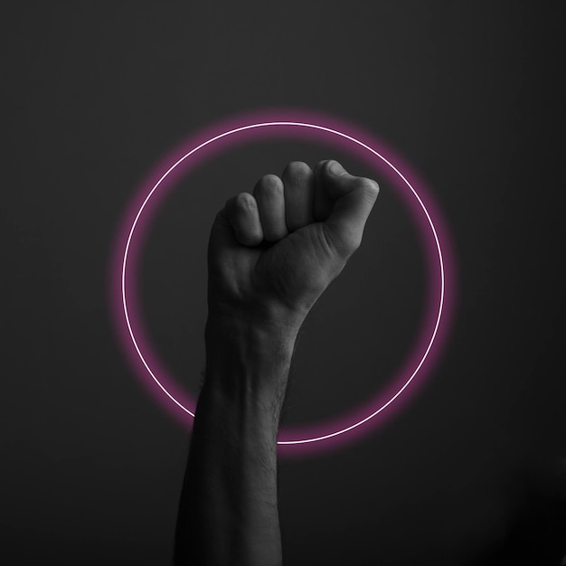 Raised clenched fist against a dark background with abstract neon light glow