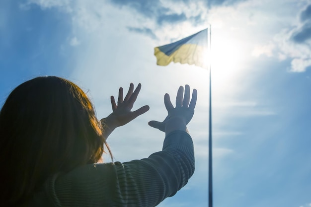 우크라이나 국기를 배경으로 하늘을 향해 손을 들어 도움을 청하고