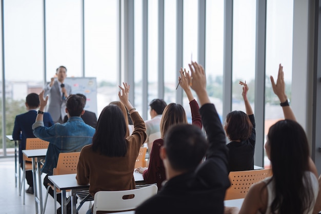 Foto sollevato le mani e le braccia di un grande gruppo in una classe di seminario per concordare con l'oratore alla sala riunioni del seminario della conferenza