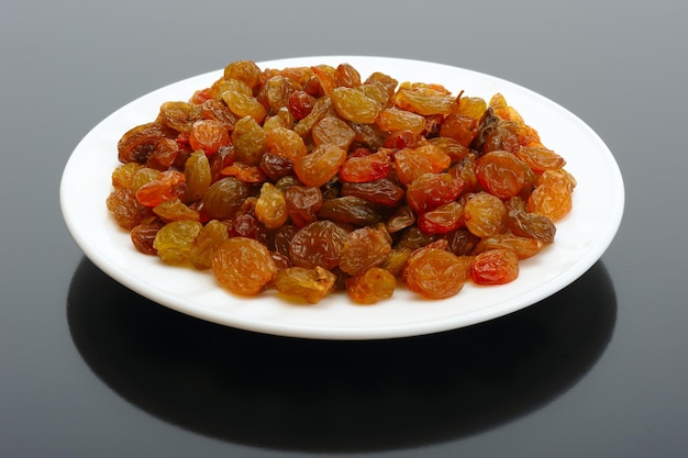 Raisin on a white plate on a black background