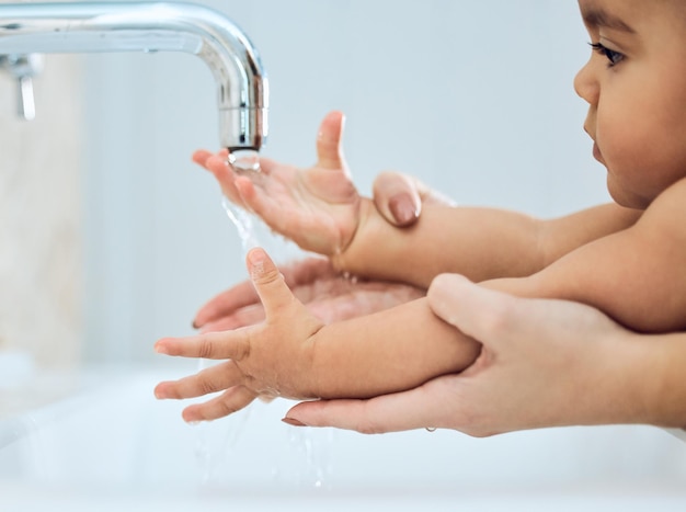 Фото Воспитание счастливого и здорового ребенка снимок женщины, моющей руки ребенку под проточной водой