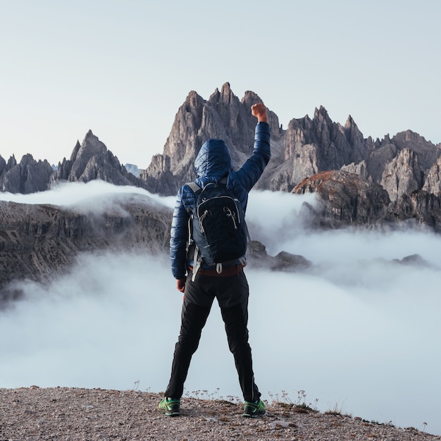 Foto alzando il pugno. uomo escursionista ha alzato le mani sulle bellissime montagne di luce del giorno piene di nebbia.