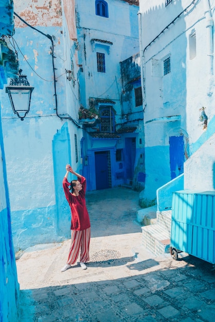 Raising hands up a girl in oriental clothes stretches on the streets of the blue city of morocco