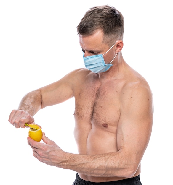 면역 및 건강 관리 개념을 높입니다. 흰색 배경 위에 레몬을 자르는 보호 마스크를 쓴 남자