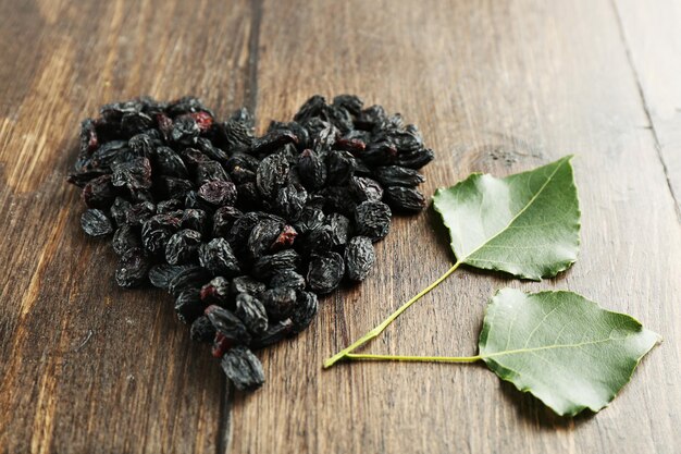 Raisins arranged in heart shape on wooden background