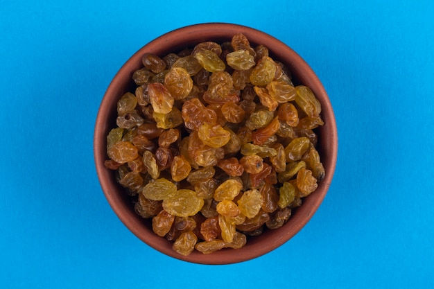 Photo raisins in a bowl on a blue.