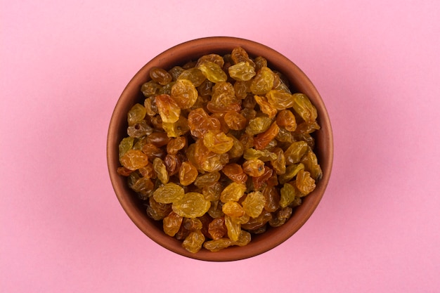 Raisins in a bowl on pink