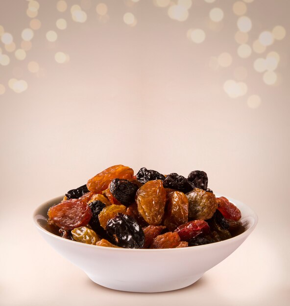 Raisins into a bowl on beige background.