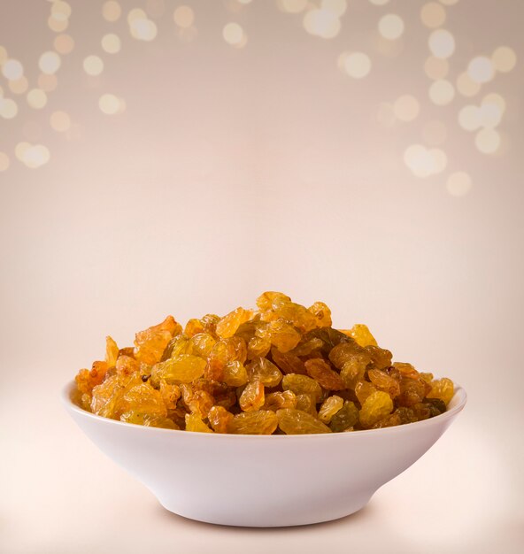 Raisins into a bowl on beige background.