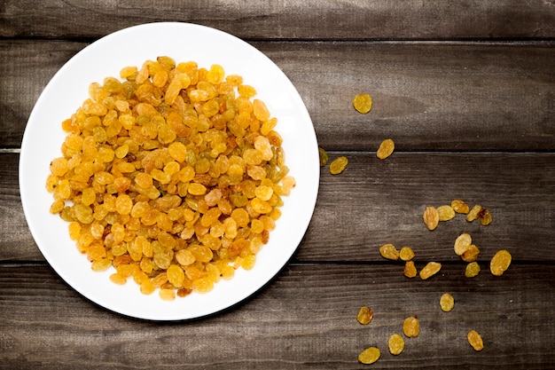 Raisins scattered from a plate on a wooden table.