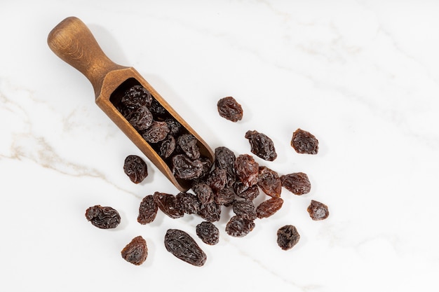 Raisins and scoop isolated on White marble surface. Dried grape. Copy space