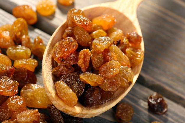 Raisins in spoon on wooden table closeup