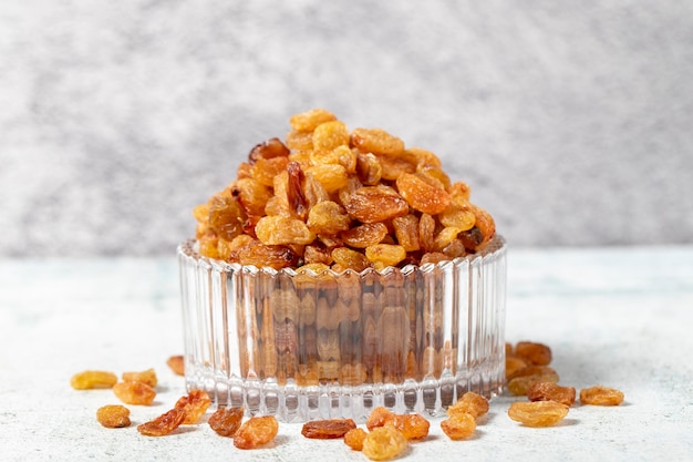 Raisins on stone background Organic yellow raisins in a glass bowl Dried healthy nuts close up