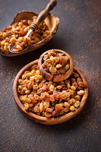 Raisins in wooden bowl on rusty background