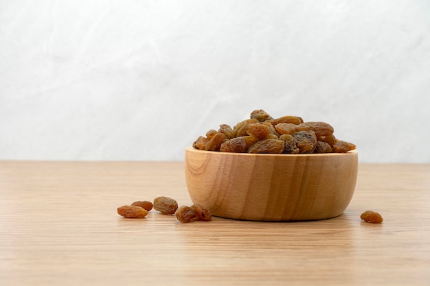 Raisins in wooden bowl on wooden texture background Dry raisins Bulk raisins grains