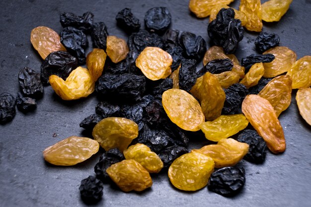 Photo raisins, yellow, blue, black, golden raisins close-up on a black background. vega food, macro foto