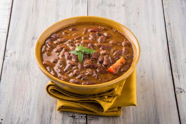 Rajma Or Razma는 향신료와 함께 걸쭉한 육즙에 익힌 붉은 강낭콩으로 구성된 인기 있는 북부 인도 음식입니다. 제라 라이스 & 그린 샐러드와 함께 그릇에 제공