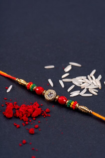 Rakhi with rice grains and kumkum on black background