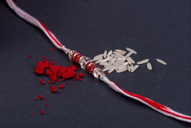 Rakhi with rice grains and kumkum on black background