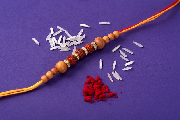 Rakhi with rice grains and kumkum. An Indian festive background