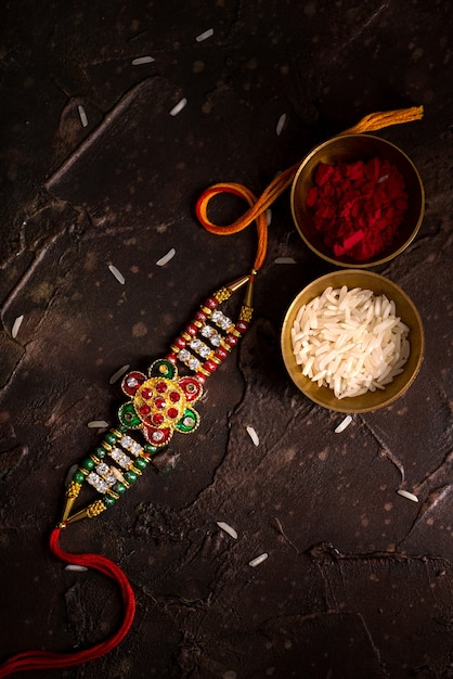 Raksha Bandhan-achtergrond met een elegante Rakhi, rijstkorrels en Kumkum