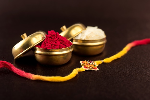 Raksha bandhan-achtergrond met een elegante rakhi, rijstkorrels en kumkum