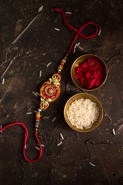 Raksha Bandhan background with an elegant Rakhi, Rice Grains and Kumkum