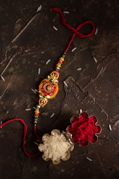 Raksha Bandhan background with an elegant Rakhi, Rice Grains and Kumkum