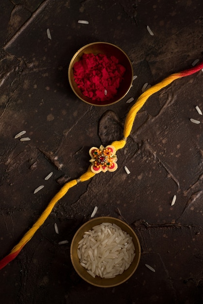 Raksha Bandhan background with an elegant Rakhi, Rice Grains and Kumkum