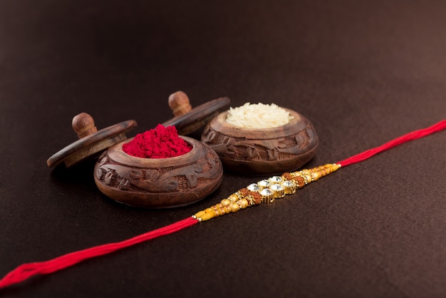 Sfondo raksha bandhan con un elegante rakhi, chicchi di riso e kumkum
