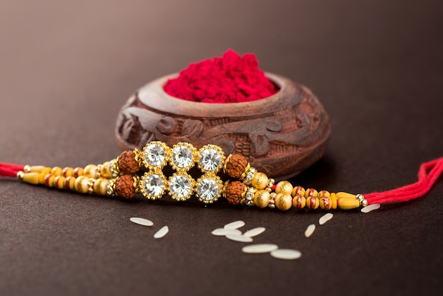 Raksha Bandhan background with an elegant Rakhi, Rice Grains and Kumkum