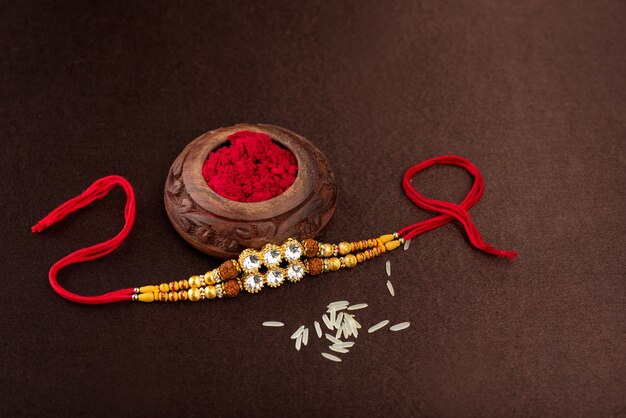 Photo raksha bandhan background with an elegant rakhi, rice grains and kumkum