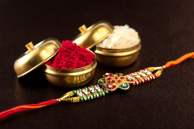 Raksha Bandhan background with an elegant Rakhi, Rice Grains and Kumkum