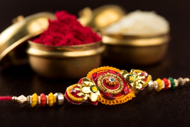 Raksha Bandhan background with an elegant Rakhi, Rice Grains and Kumkum