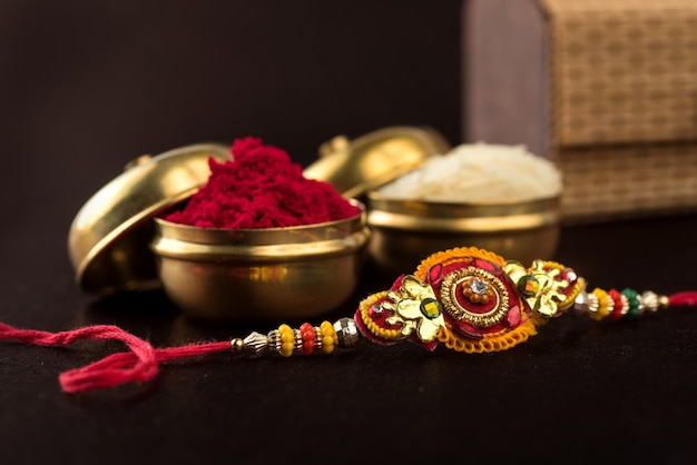 Raksha Bandhan background with an elegant Rakhi, Rice Grains and Kumkum