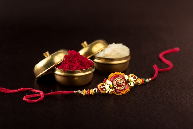 Raksha bandhan-compositie met een elegante rakhi, rijstkorrels en kumkum. een traditionele indiase polsband die een symbool is van liefde tussen broers en zussen.