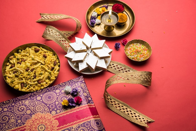 사진 raksha bandhan festival greetings: kaju katli barfi 또는 burfi와 멋진 밴드와 푸자 thali로 가득 찬 접시를 사용하여 만든 개념적 rakhi. 선택적 초점