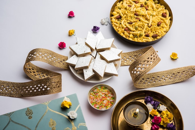 Raksha bandhan Festival Greetings: Kaju Katli Barfi 또는 Burfi와 멋진 밴드와 푸자 Thali로 가득 찬 접시를 사용하여 만든 개념적 Rakhi. 선택적 초점