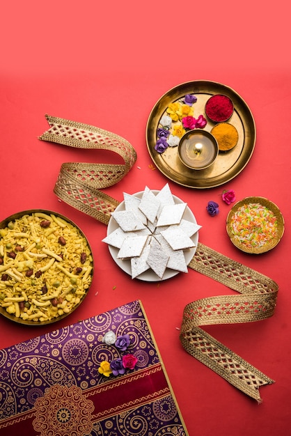 Raksha bandhan Festival Greetings: Kaju Katli Barfi 또는 Burfi와 멋진 밴드와 푸자 Thali로 가득 찬 접시를 사용하여 만든 개념적 Rakhi. 선택적 초점