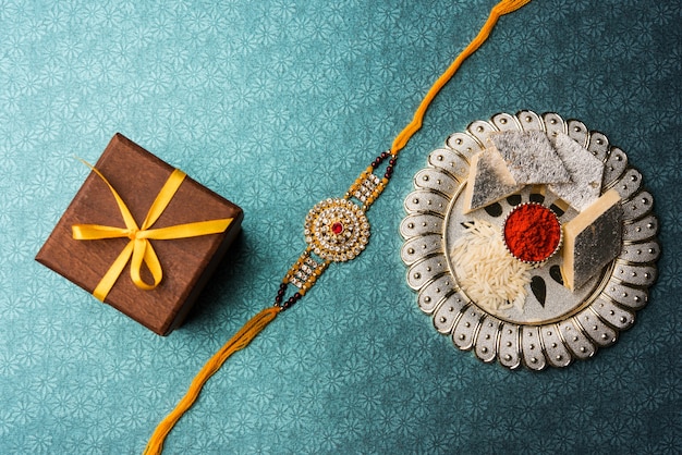 Foto raksha bandhan groet rakhi en cadeau met zoete kaju katli of mithai en rijstkorrels kumkum