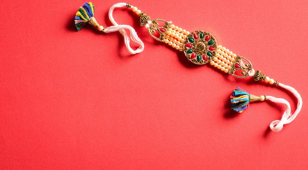 Raksha Bandhan Indian festival with beautiful Rakhi on red background