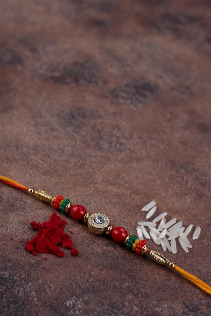 Ракша Бандхан: Ракхи с рисовыми зернами и кумкумом на каменном фоне.