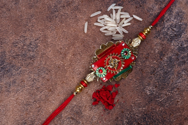 Raksha Bandhan : Rakhi with rice grains and kumkum on stone background