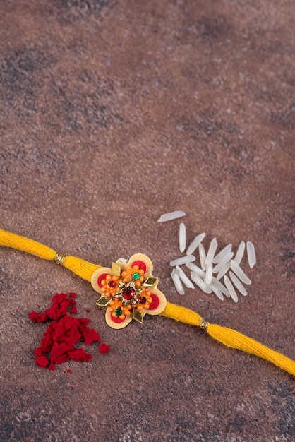 Foto raksha bandhan: rakhi con chicchi di riso e kumkum su sfondo di pietra stone