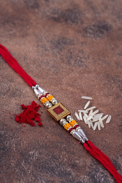 Raksha Bandhan : Rakhi with rice grains and kumkum on stone background