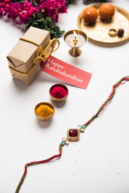 Photo raksha bandhan / rakshabandhan rakhi with haldi kumkum rice, sweet mithai, gift box, selective focus